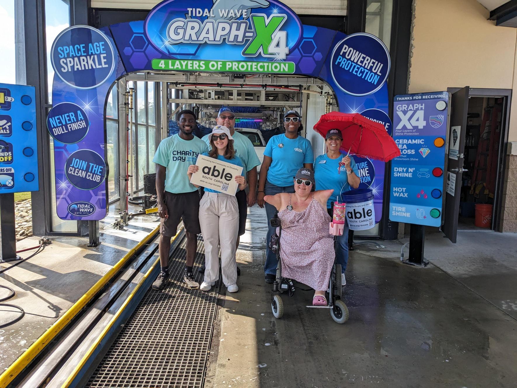 Able SC staff pose in the car wash bay with the Tidal Wave staff.