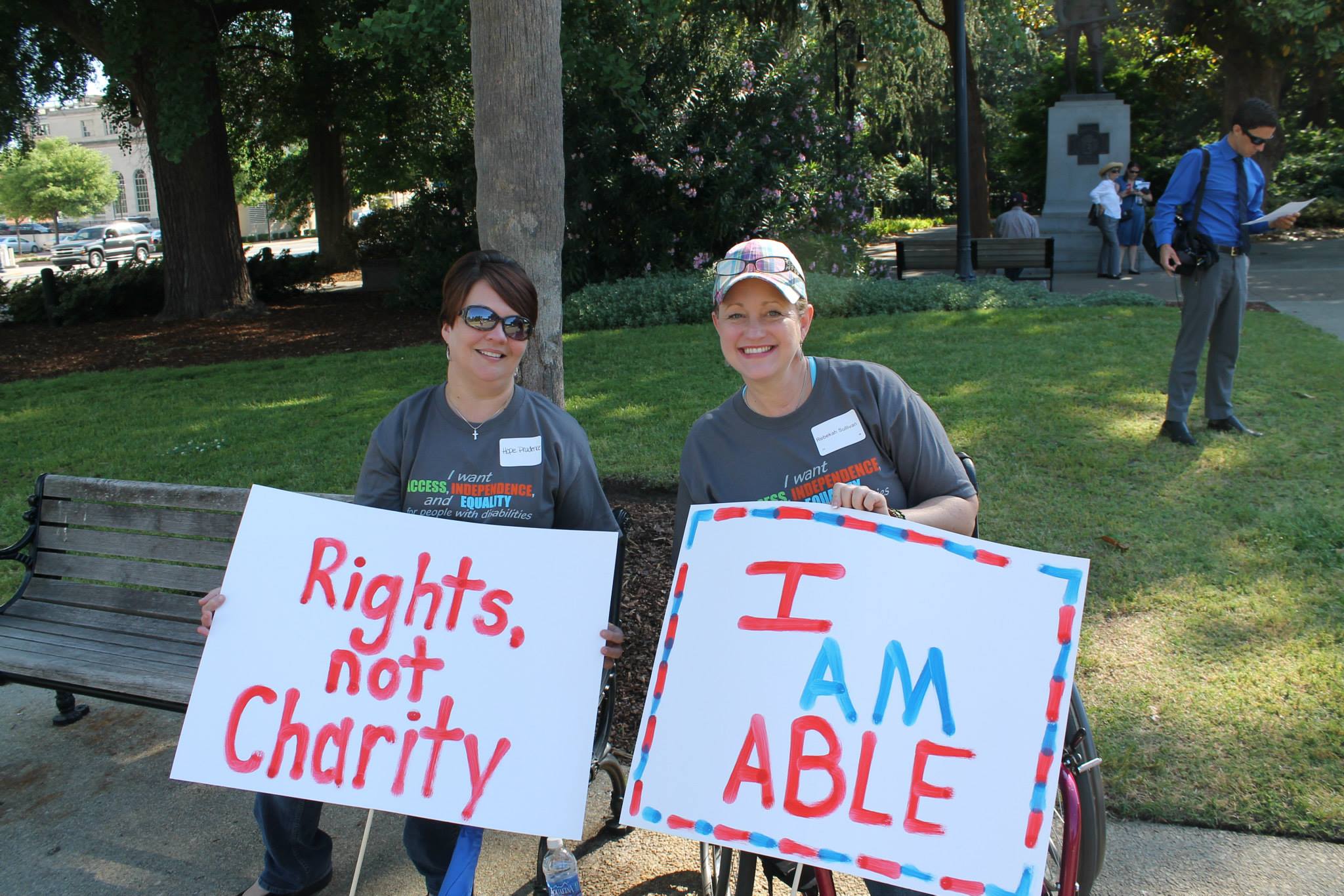 Two women holding signs. Text reads: Rights, not charity. I AM ABLE.