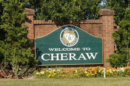 The Welcome to Cheraw sign on a brick wall surrounded by trees and bushes
