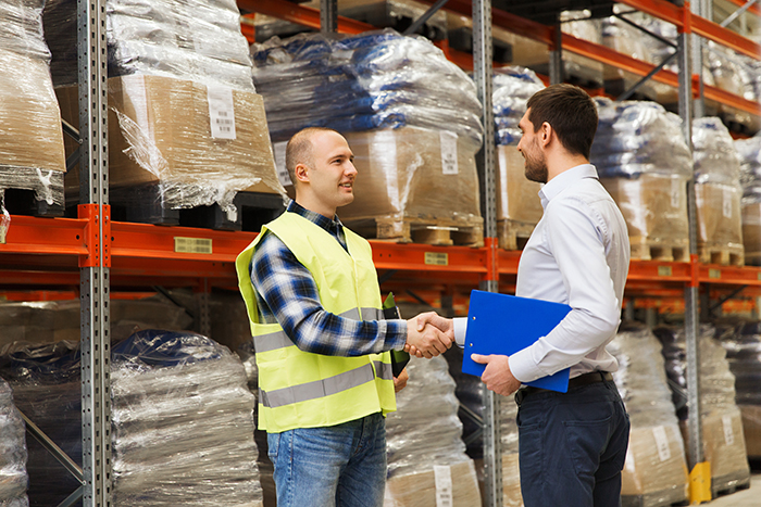 Two men shaking hands in a warehouse.