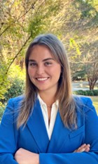 Molly Dickerson, Able SC Public Health intern. Molly is a young, white woman with long brown hair. In this photo she is smiling, wearing a blue blazer and white shirt.